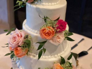 4 tier white round wedding cake 4 tier round wedding cake smoothly iced with white fondant and the layer edges are finished with piped white pearls. Each layer is decorated with a bunch of roses of various shades of pink. Each layer has roses in a single location alternating from right to left, starting at the bottom on the right.